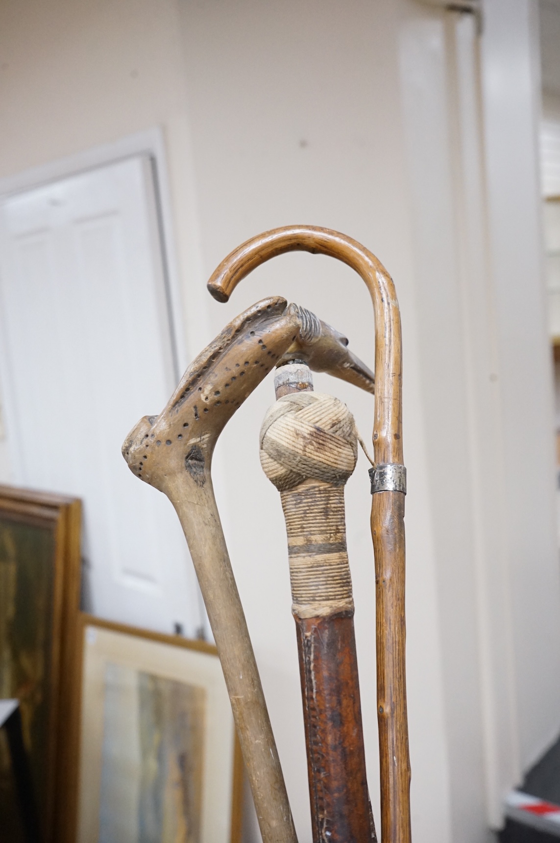 Five walking sticks to include two with rope work handles and one carved in the form of a dog's head, largest 94cm in length